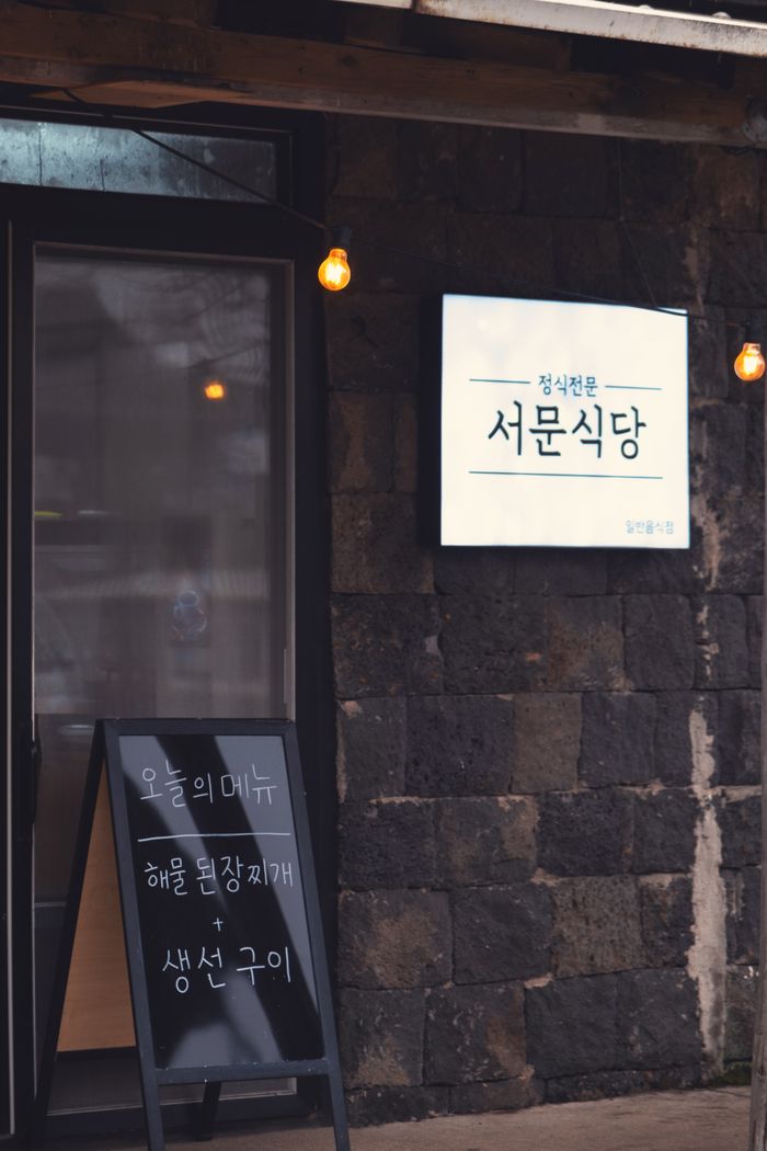 Korean restaurant entrance with menu board and warm lighting, perfect for a cozy evening.