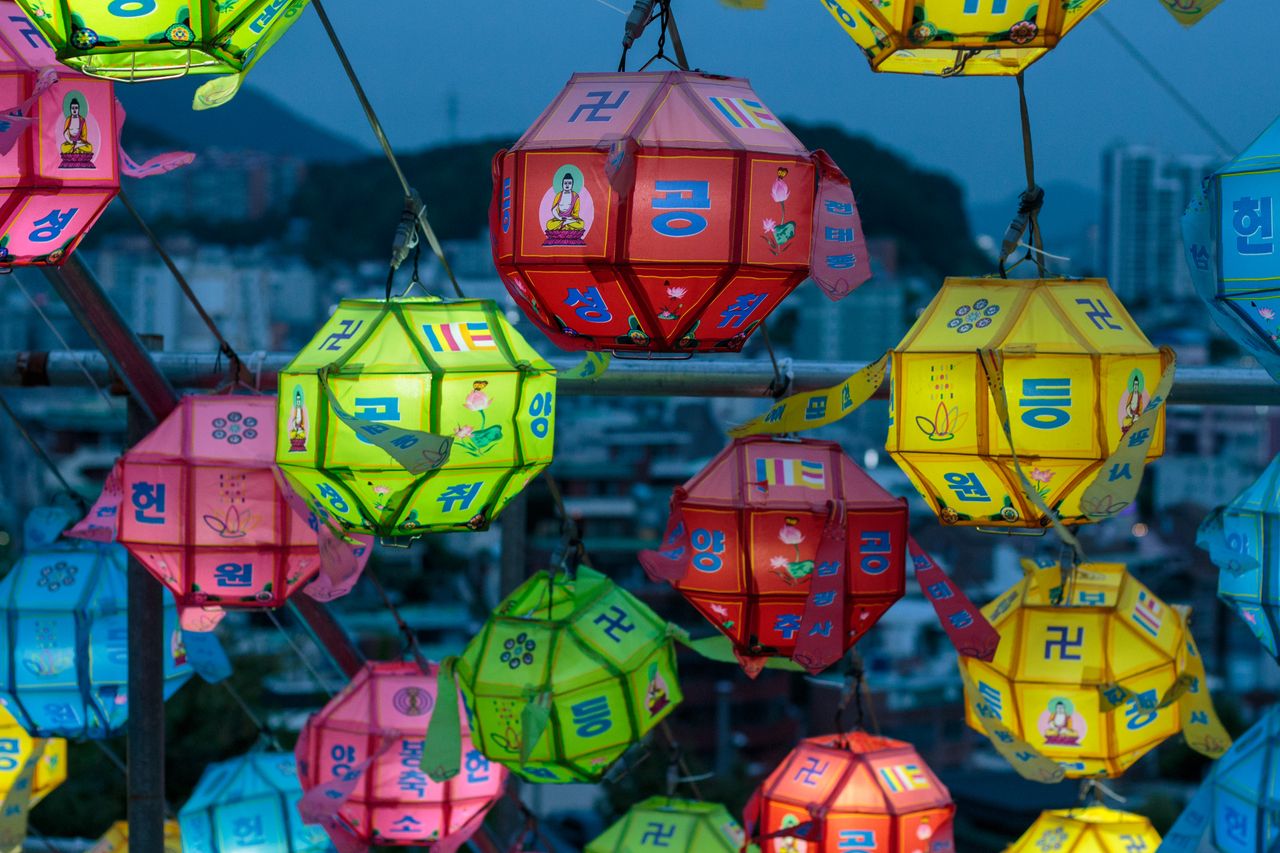 Vibrant paper lanterns hanging outdoors at night, capturing cultural festivity and city background.