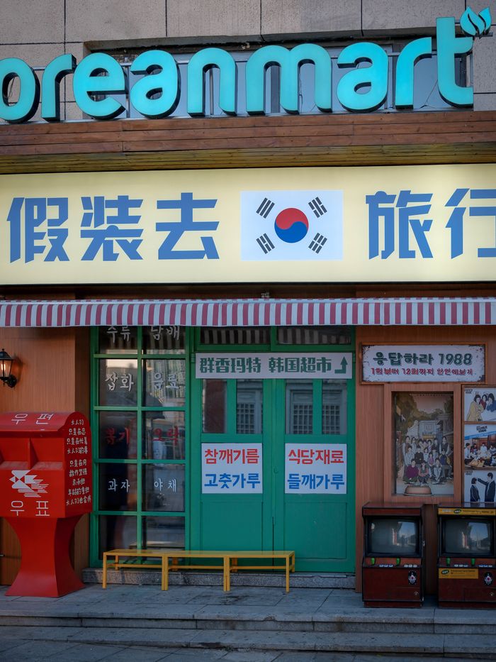 Exterior view of a retro Korean mart with signs in Korean, featuring classic storefront decor and vintage elements.